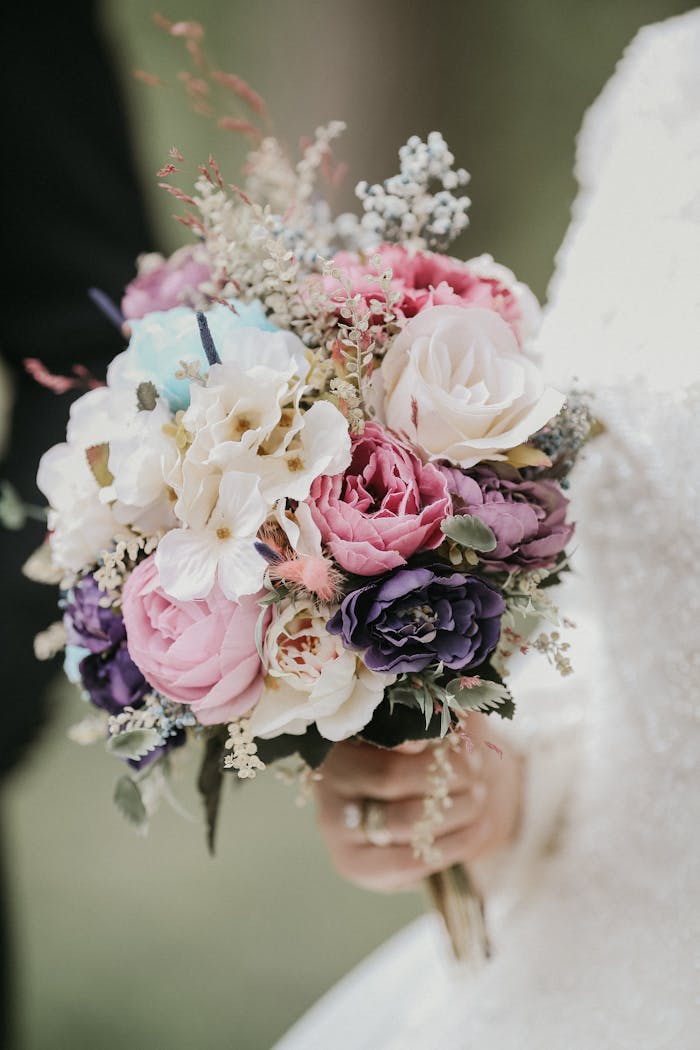 Close-up of a bride holding a vibrant bouquet of mixed flowers in soft lighting.