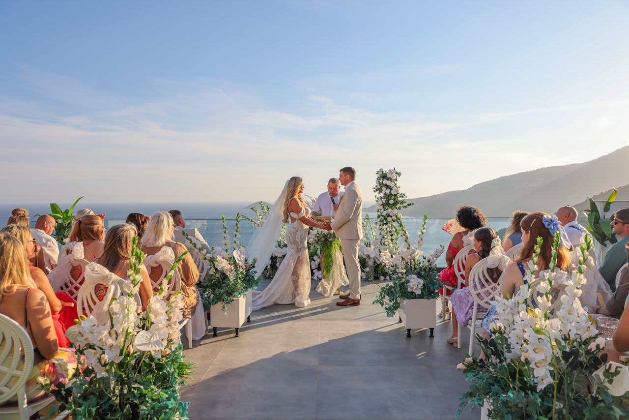 Elegant outdoor wedding ceremony with ocean view and floral decor.