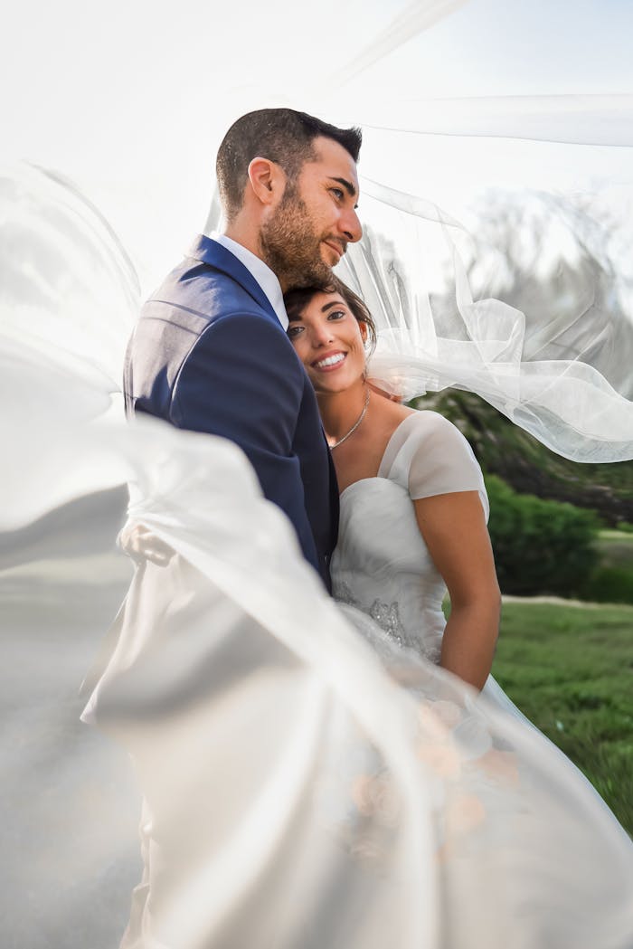 Bride and groom embrace under a flowing veil in scenic Lake Como, Italy.