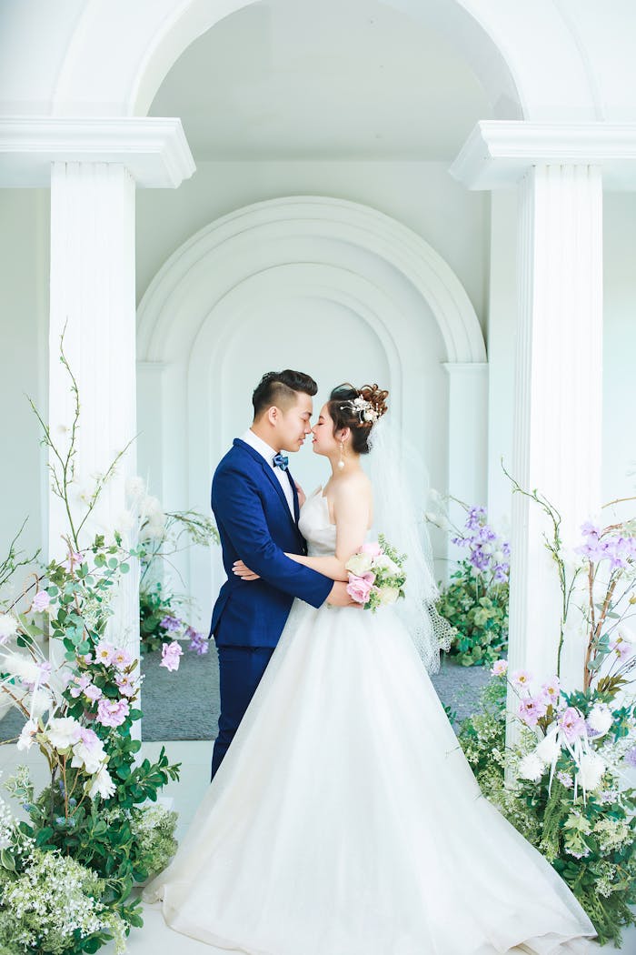 A stylish Asian groom and bride share a loving embrace at their indoor wedding ceremony.